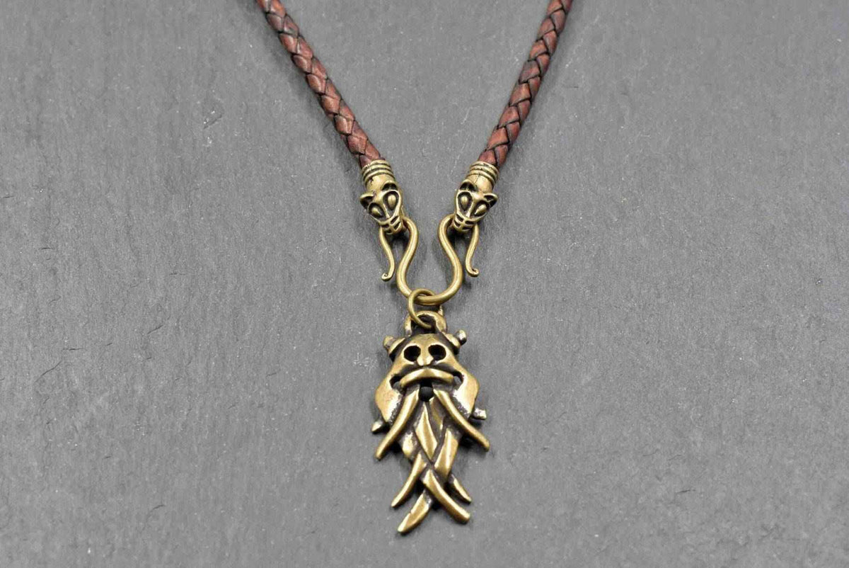 Aarhus-Masken-Kette braun mit bronze am geflochtenen Lederband

Der Maskenanhänger aus ZAMAK hängt an einem Omega-Haken zwischen zwei dekorativen Tierkopfabschlüssen. 