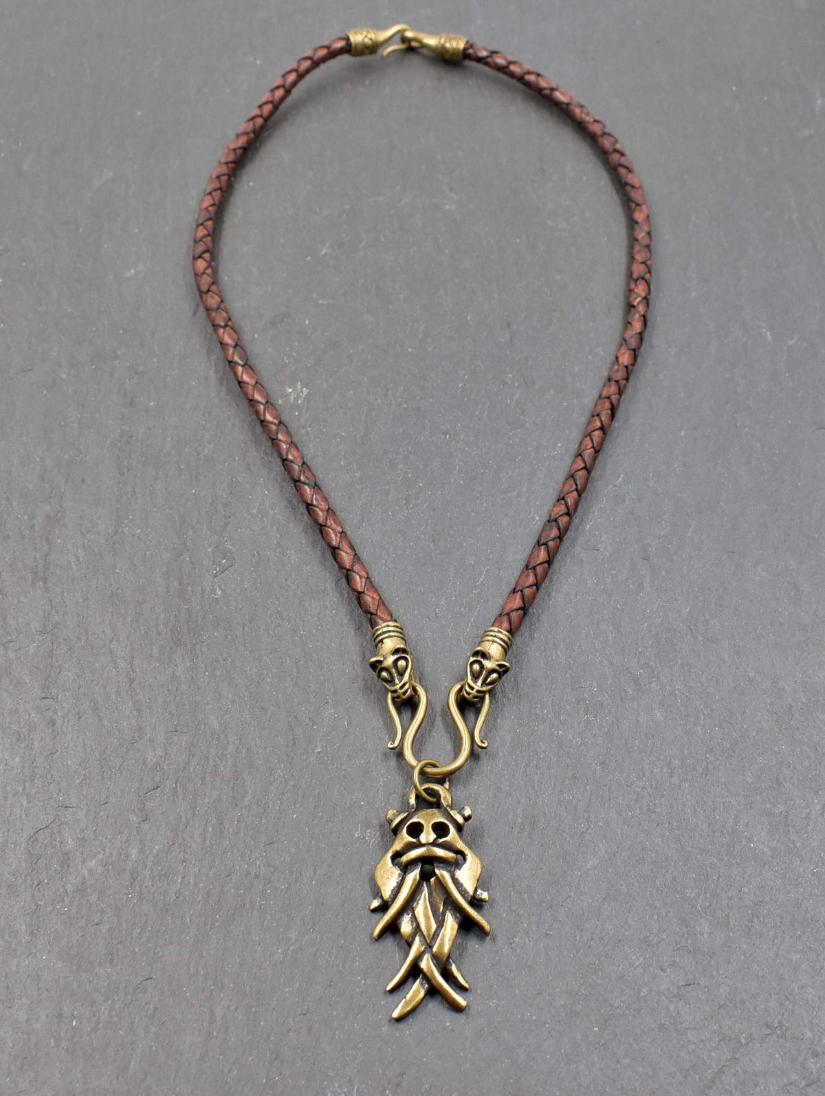 Aarhus-Masken-Kette braun mit bronze am geflochtenen Lederband

Der Maskenanhänger aus ZAMAK hängt an einem Omega-Haken zwischen zwei dekorativen Tierkopfabschlüssen. 