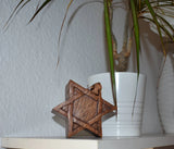 Stern-Puzzledose aus Holz mit Geheimfach auf einem Regal neben einer Pflanze