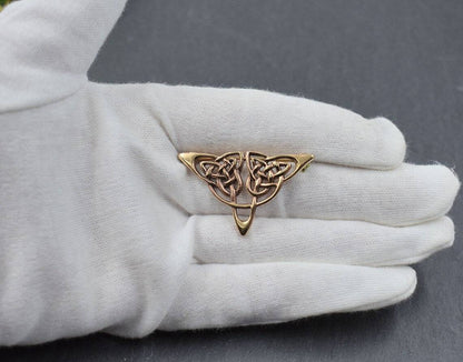 Kleine Brosche mit Triquetra aus Bronze auf der Hand