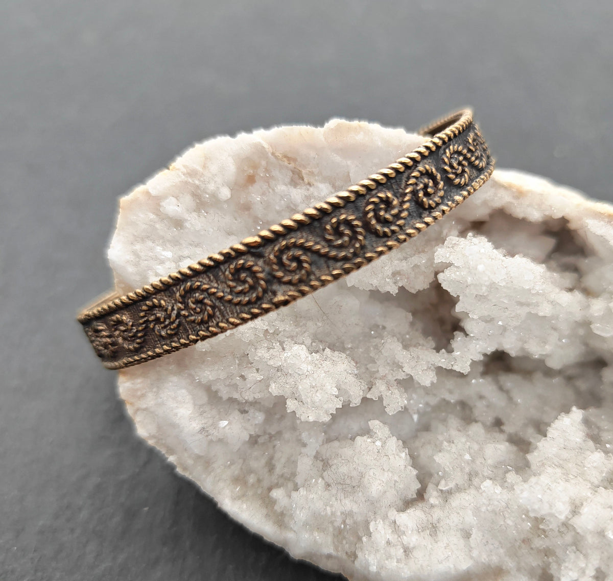 Keltischer Bronzearmreif mit S-Spiral-Ornament

Dieser offene Bronzearmreif aus Schmuckbronze ist rundum mit einem geschwungenen Spiral- und Rankenmuster verziert. Die erhabenen Ornamente heben sich durch die dunkel abgesetzten Vertiefungen deutlich von der warmen Bronzeoberfläche ab.