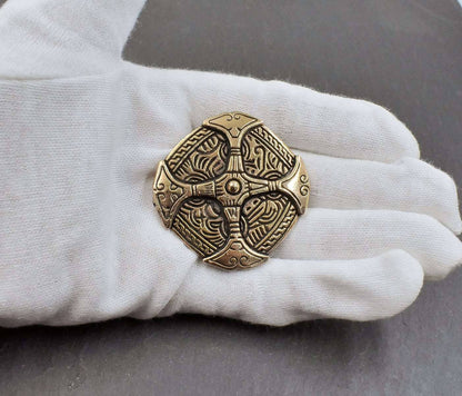 Große keltische Brosche in Schildform mit einem keltischen Muster und aufgebrachten Kreuz, aus massiver Bronze auf der Hand