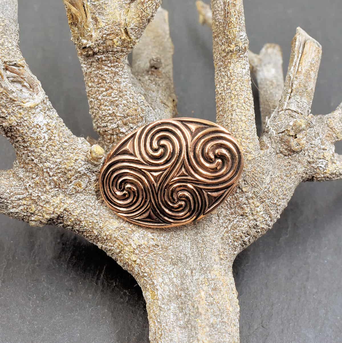 Keltische Brosche mit Spiralmuster aus Bronze - aus der Latenézeit, auf einem Ast